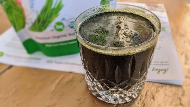 A glass of organic green superfood powder with 44 natural ingredients for daily wellness